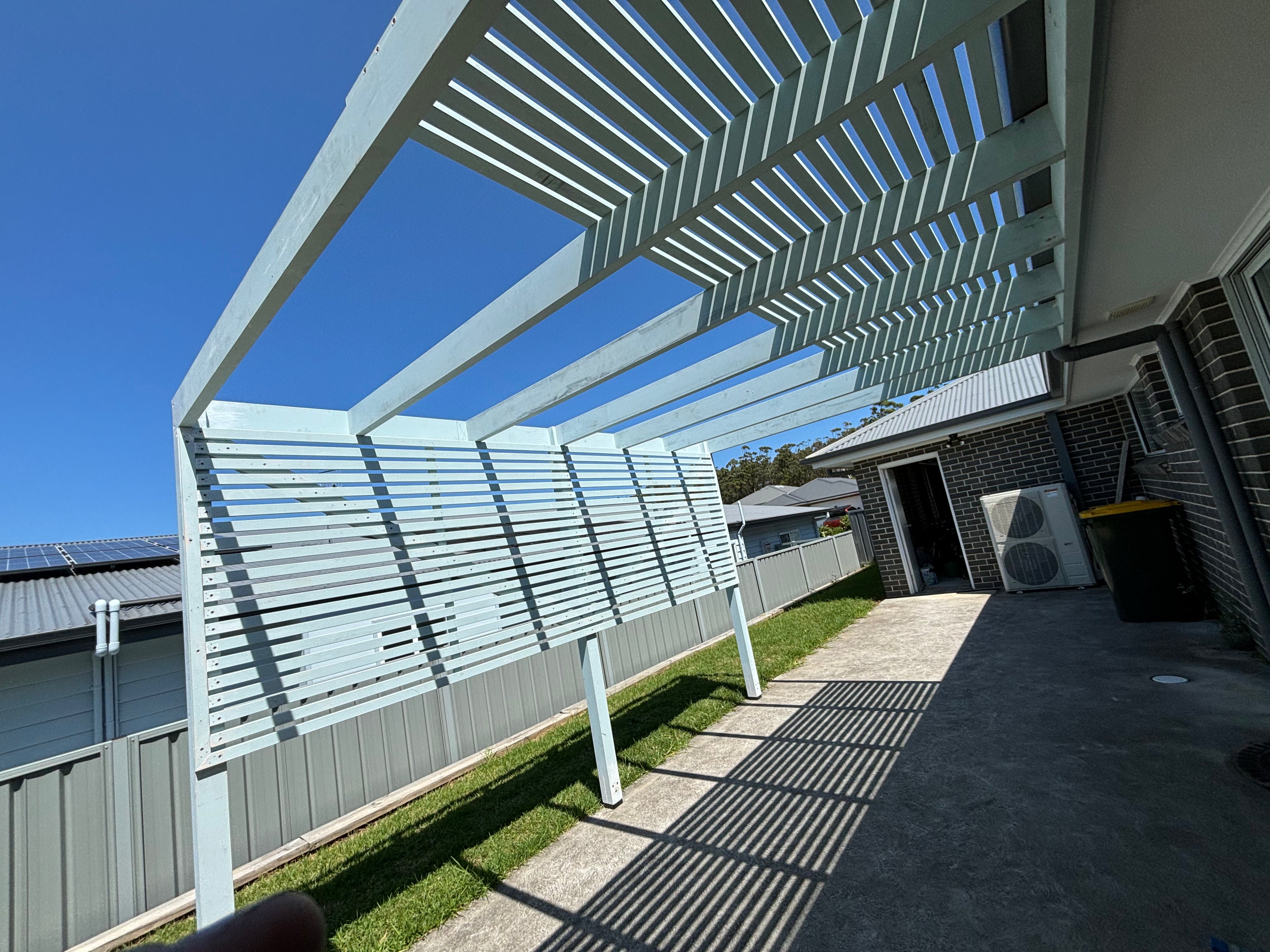 Patio area with a pergola and outdoor furniture under a clear blue sky.